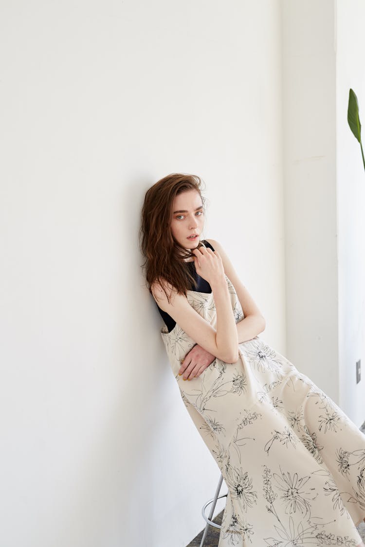 Woman Sitting On A Stool And Leaning Against A Wall 