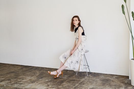 Woman in a White Dress Sitting on a Stool 