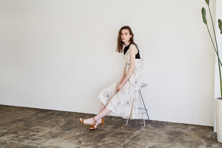 Woman In A White Dress Sitting On A Stool 