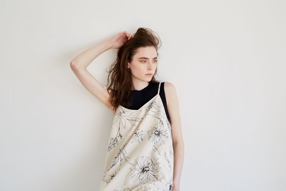 A thoughtful woman in a floral dress with hand in hair, offering copy space.