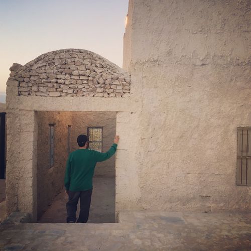 Free A person in green explores traditional architecture in Kuwait City at sunset. Stock Photo
