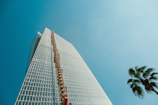 晴朗的天空下，棕榈树映衬着以色列拉马特甘一座现代摩天大楼的低角度视图