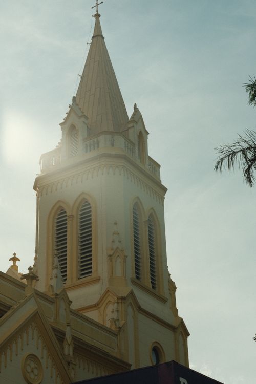 Free Impressive Gothic Revival church bell tower captured on a sunny day with a subtle afternoon glare. Stock Photo