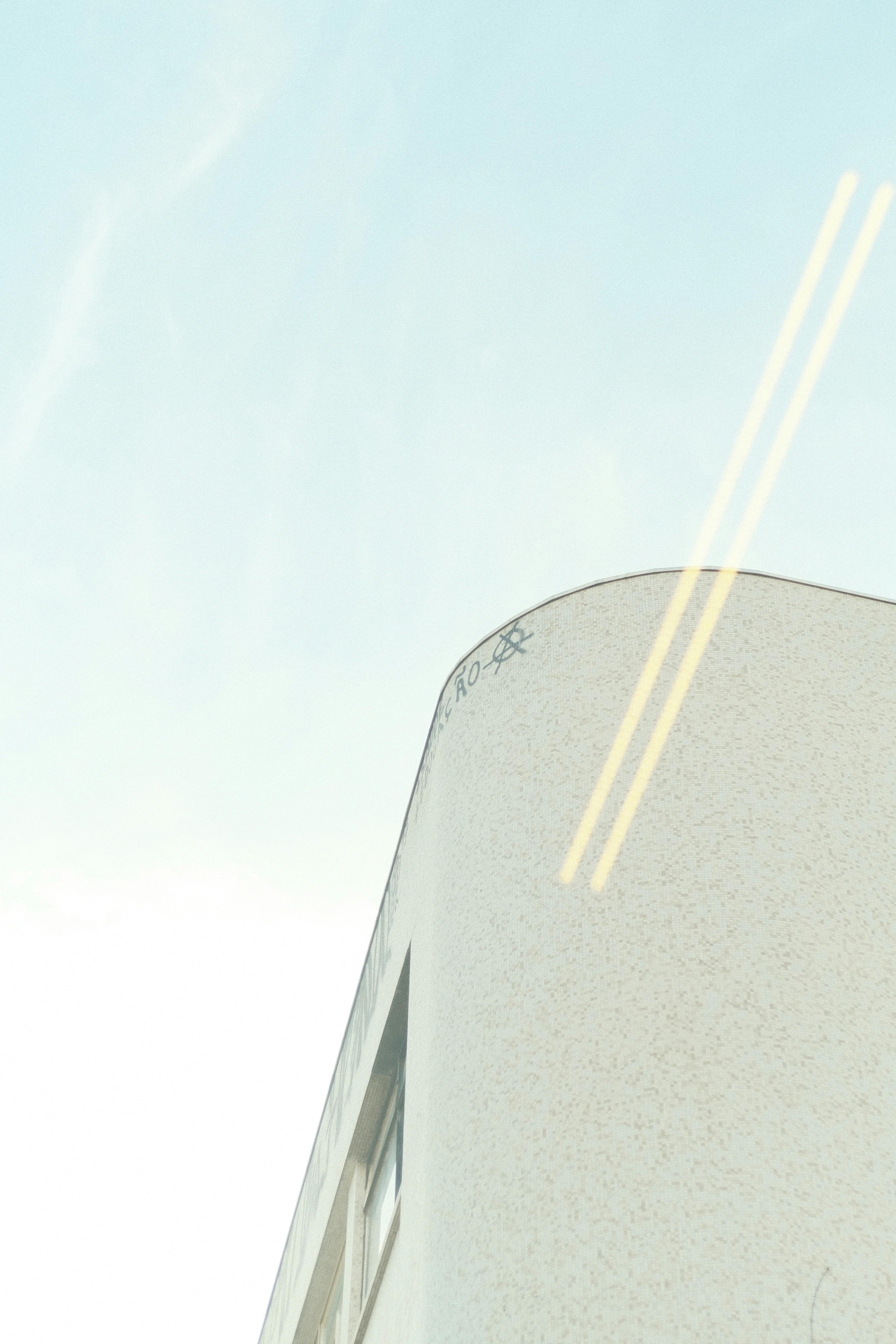 Free Minimalist architecture featuring a rounded building corner with glass windows against a clear blue sky. Stock Photo