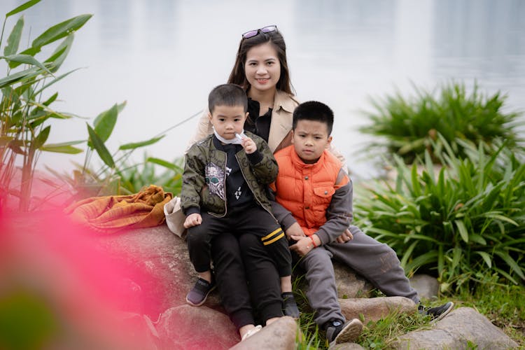 Mother And Children Sitting Together On A Big Rock