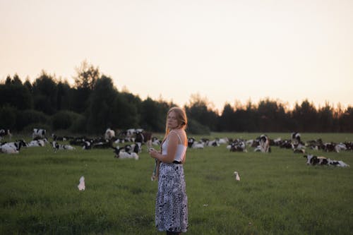 Blonde Woman Posing on Pasture with Cows