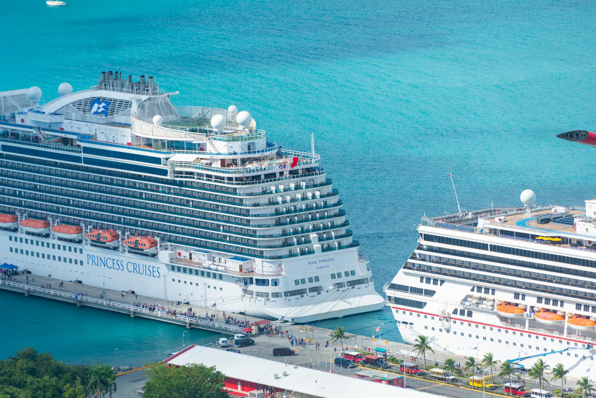 Aerial view of grand cruise ships docked at a tropical pier with turquoise waters.