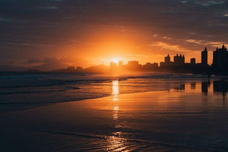 Sunlight Over City On Sea Shore At Sunset