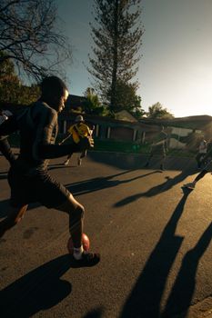 Energetic group of young men playing soccer on a street in South Africa during sunset, capturing the spirit of recreation and motion.