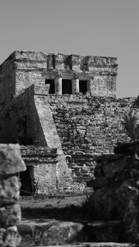 Historic stone ruins under clear sky in black and white, depicting ancient architecture.