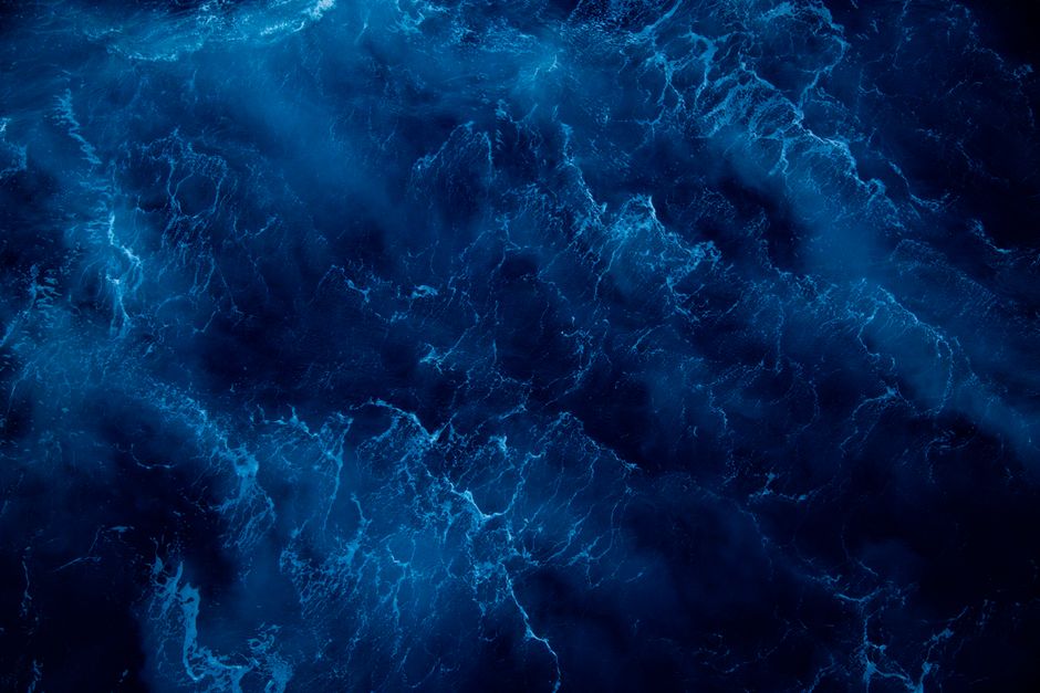 Captivating top view of dark blue ocean water with wavy patterns creating a mesmerizing texture.