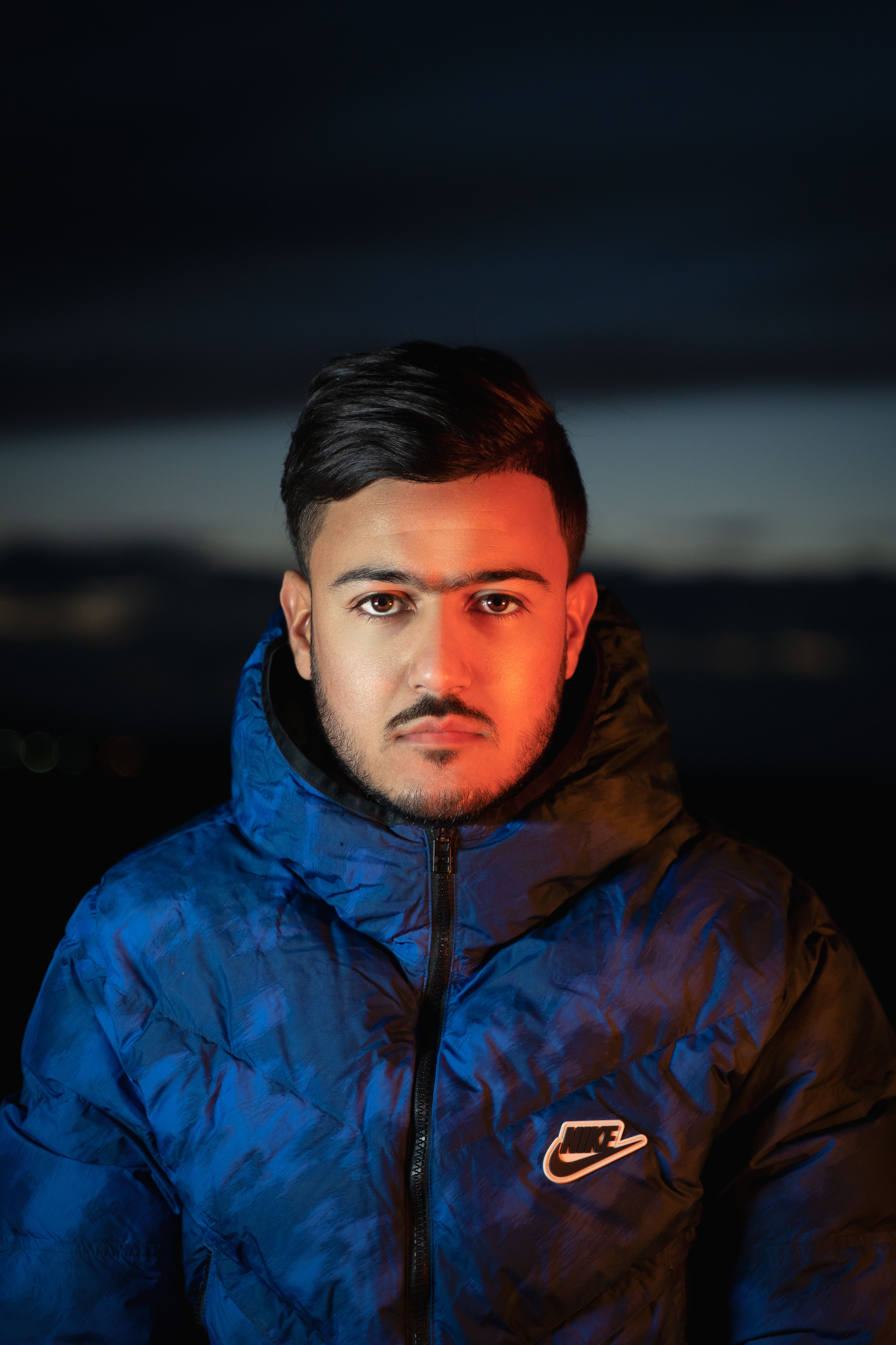 Stylish portrait of a man wearing a blue jacket against a twilight sky, New York City.