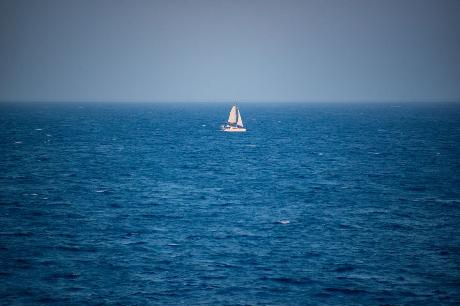 A solitary sailboat voyages across the calm blue seas, capturing the essence of maritime adventure.