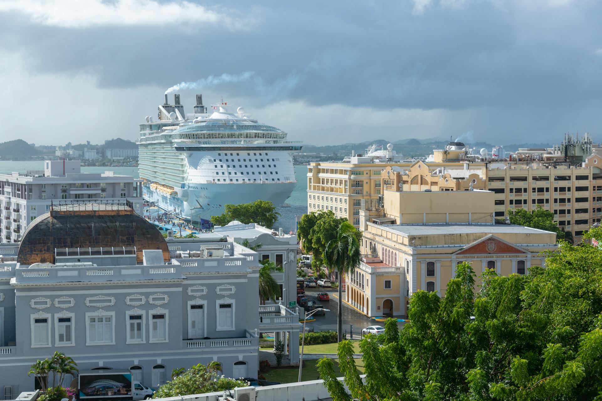 A large cruise ship moored in a vibrant urban harbor, surrounded by historic architecture.