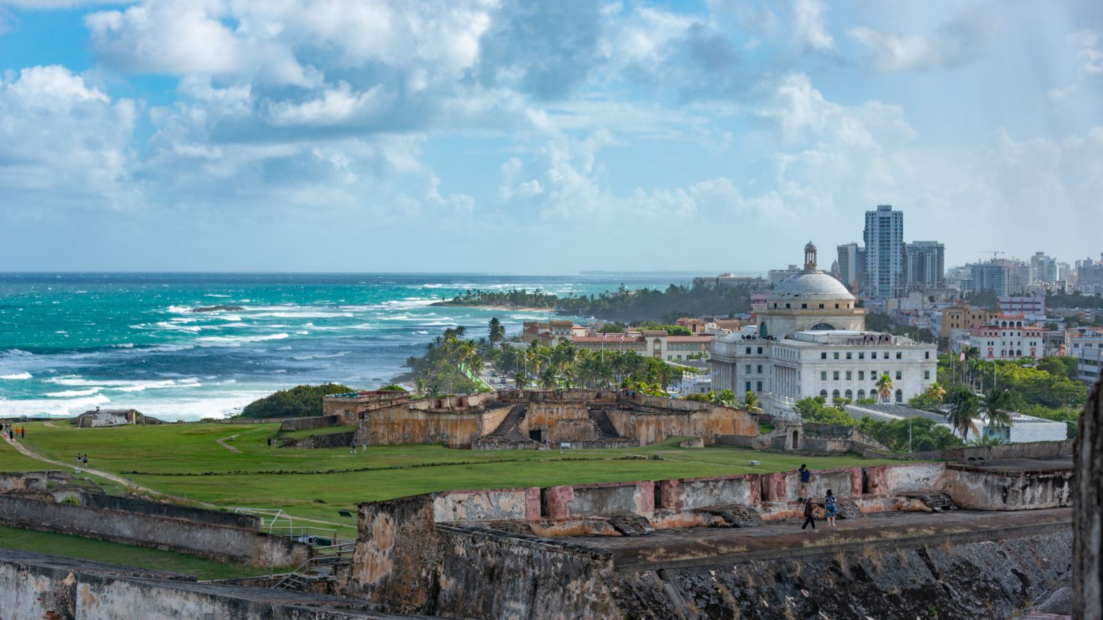 Explore the stunning view of San Juan's historic fort with ocean backdrop under a vibrant sky.