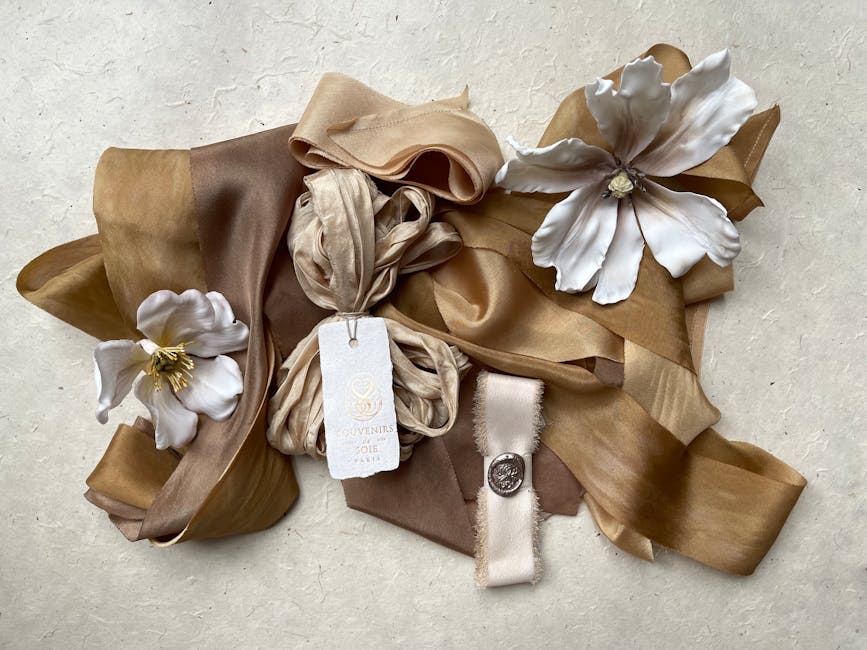 Aesthetic flat lay of beige and brown ribbons with white floral decorations, perfect for event styling.