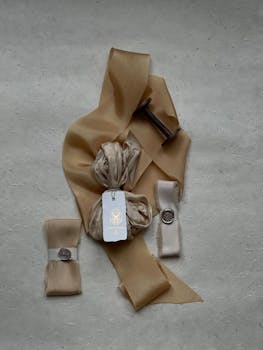 A beautifully arranged flat lay of beige fabric and ribbon on a textured gray background, with vintage elements.