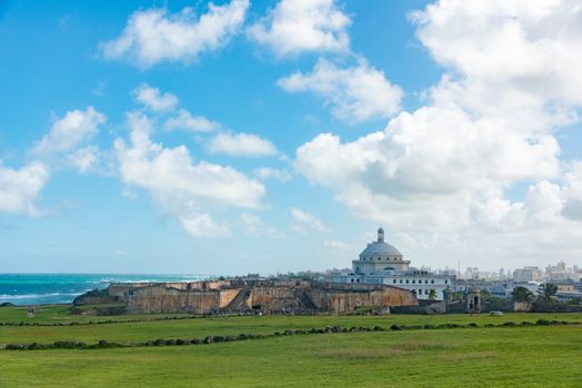 A scenic view of San Juan, featuring El Capitolio and historic fortifications under a bright blue sky.
