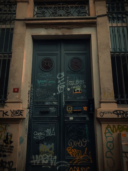Free An old doorway covered in vibrant graffiti on an urban street, providing a dramatic visual. Stock Photo