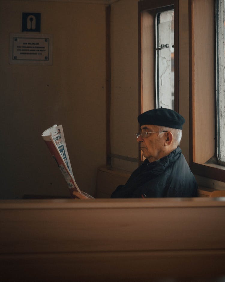 Sitting Man In A Black Beret Reading A Newspaper