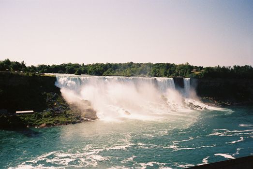 Dramatic photo of the majestic Niagara Falls with lush green surroundings.