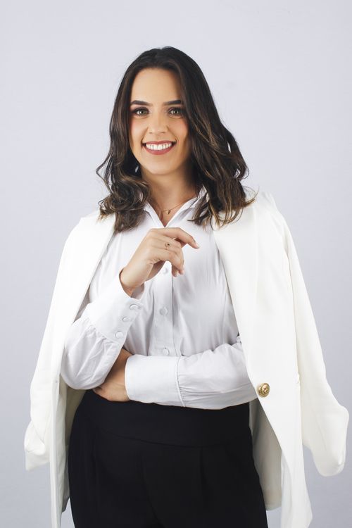 Free Confident woman in a white blazer, smiling in a studio setting with a white background. Stock Photo