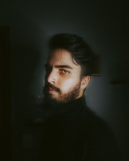 Free Dramatic side-lit portrait of a bearded man exuding mystery and introspection. Stock Photo