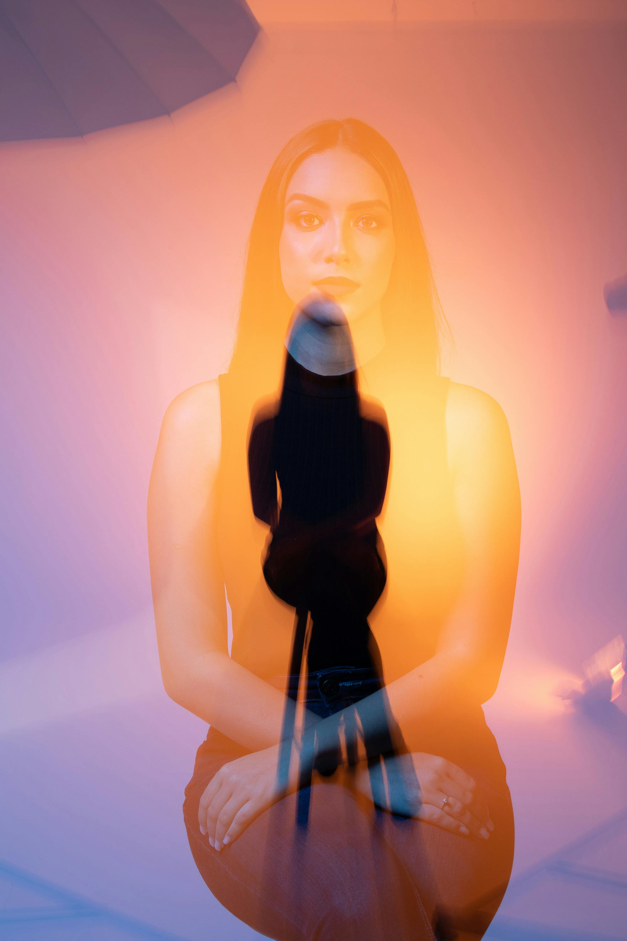 Artistic double exposure shot of a woman posing in a studio with vibrant lighting.