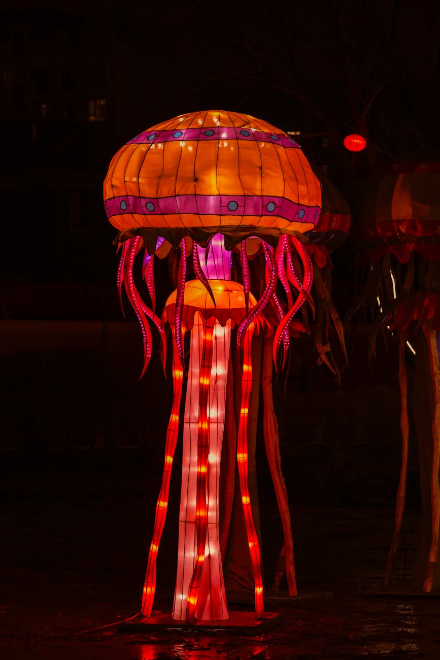 Vividly lit jellyfish sculpture glowing in the dark with vibrant red and orange lights.
