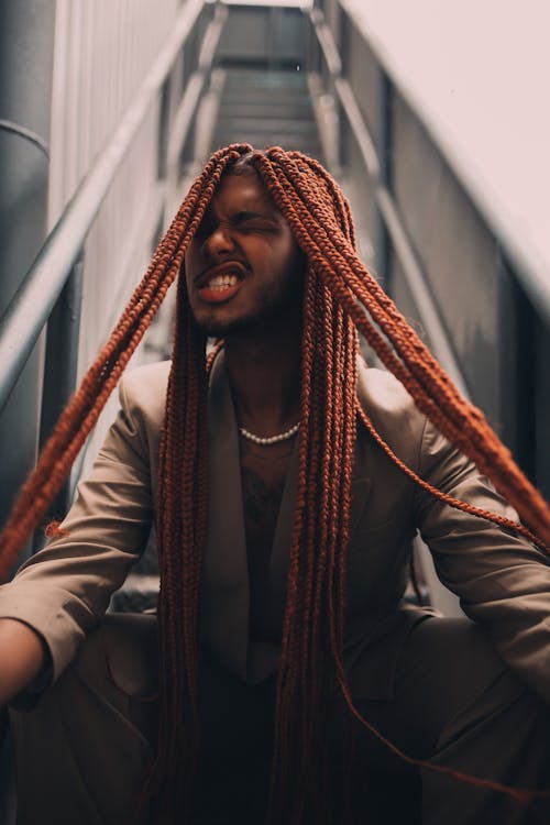 Man Sitting on the Escalator and Pulling his Long Dreadlocks 