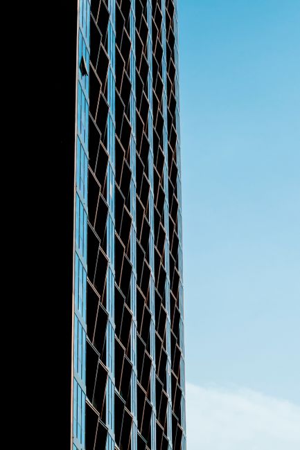 Tall modern skyscraper in Dubai with geometric patterns beneath a clear blue sky, highlighting urban architecture.