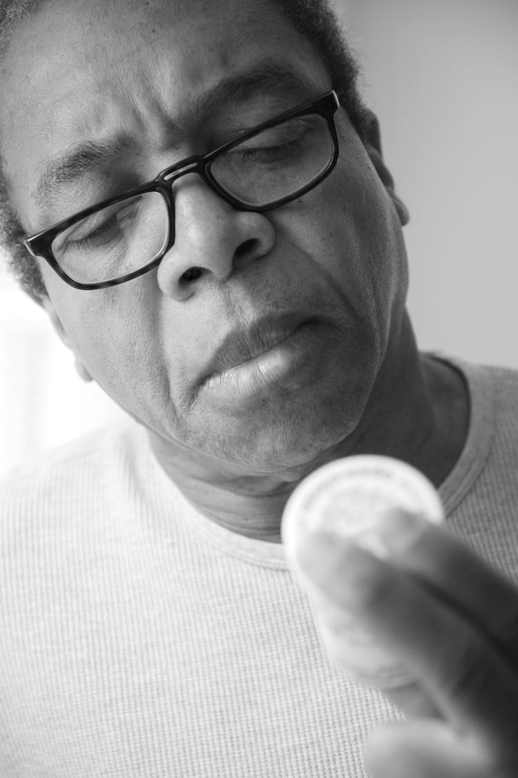 Man Wearing Eyeglasses Reading A Medicine Bottle 
