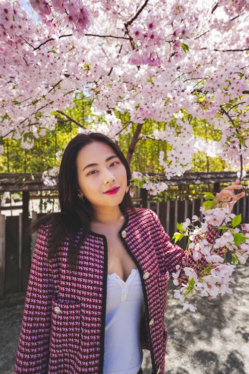 Young Woman Standing under Flowering Cherry Trees