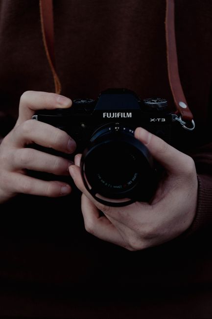 Close-up of hands holding a vintage Fujifilm camera, capturing nostalgia.