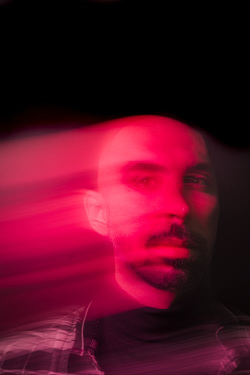 Free Blurred portrait of a bearded man with artistic pink light trails creating a dramatic effect. Stock Photo