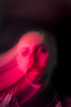 Blurry abstract portrait with pink light and motion blur, creating a surreal effect.