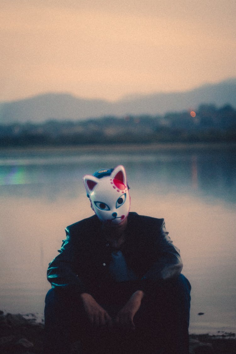 Man Sitting By River In Animal Mask