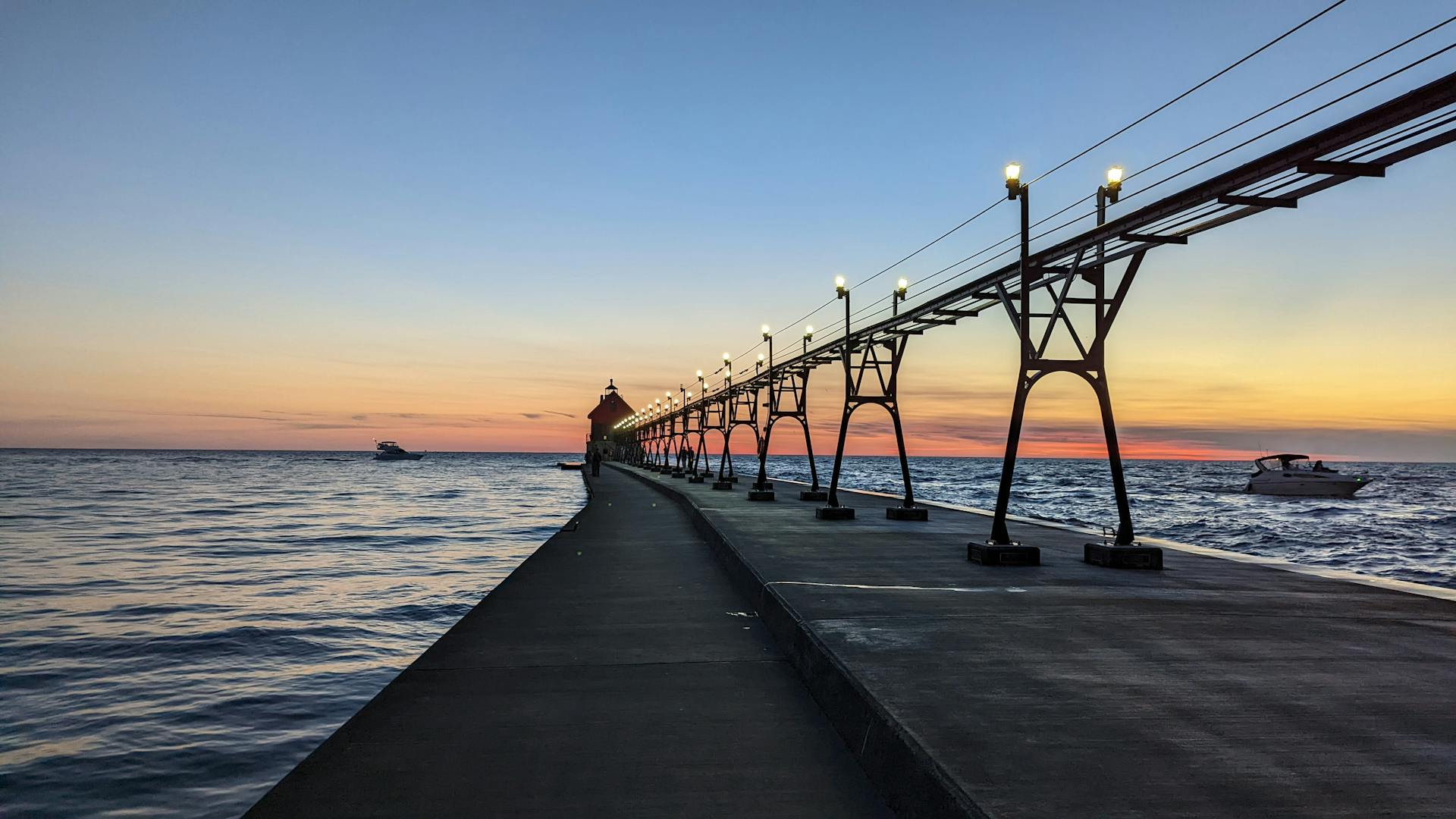 Beautiful sunset view over Lake Michigan pier with boats and calm waters.