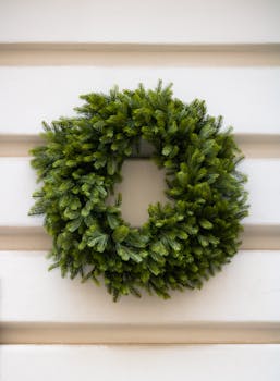 A simple evergreen wreath displayed outdoors on a white panel background, perfect for winter and holiday decor.
