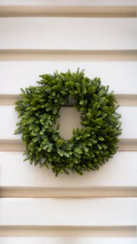 A simple green evergreen wreath on a white wooden wall indoors.