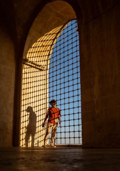 A man stands in an ancient archway in Mardin, casting a shadow at sunset.
