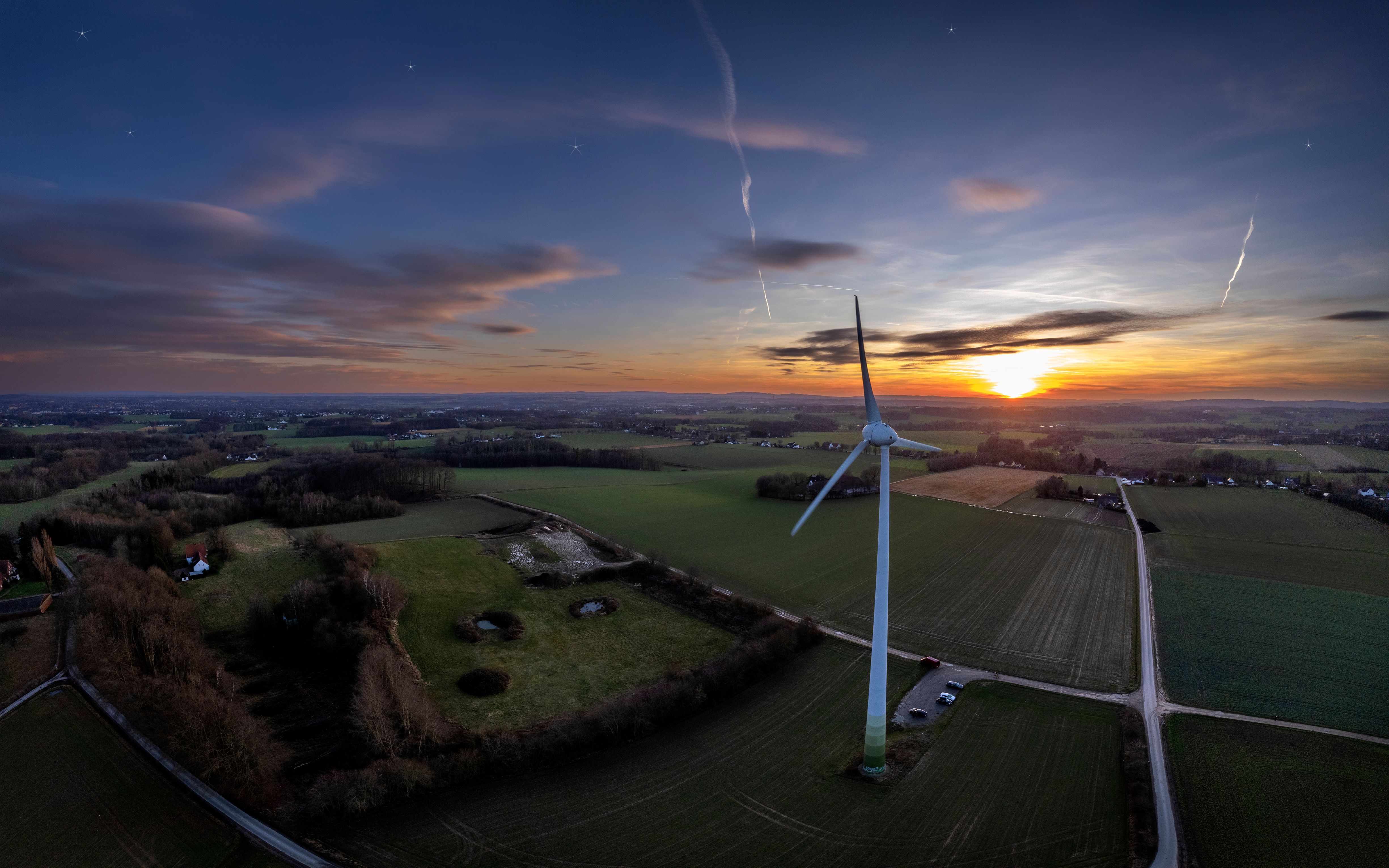 Vindturbiner i urbant landskap ved solnedgang