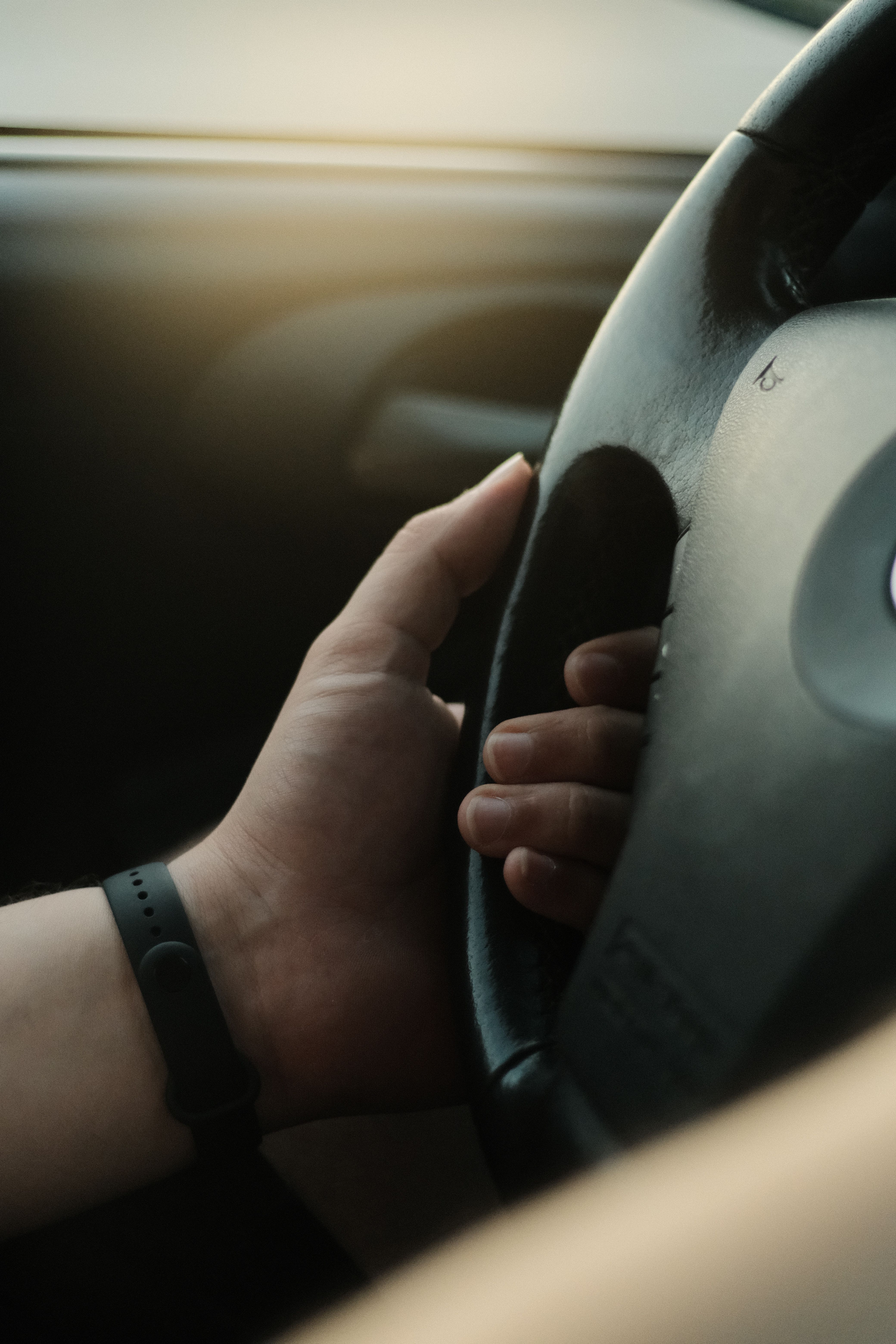 Close-up of a hand gripping a steering wheel, ready to drive.