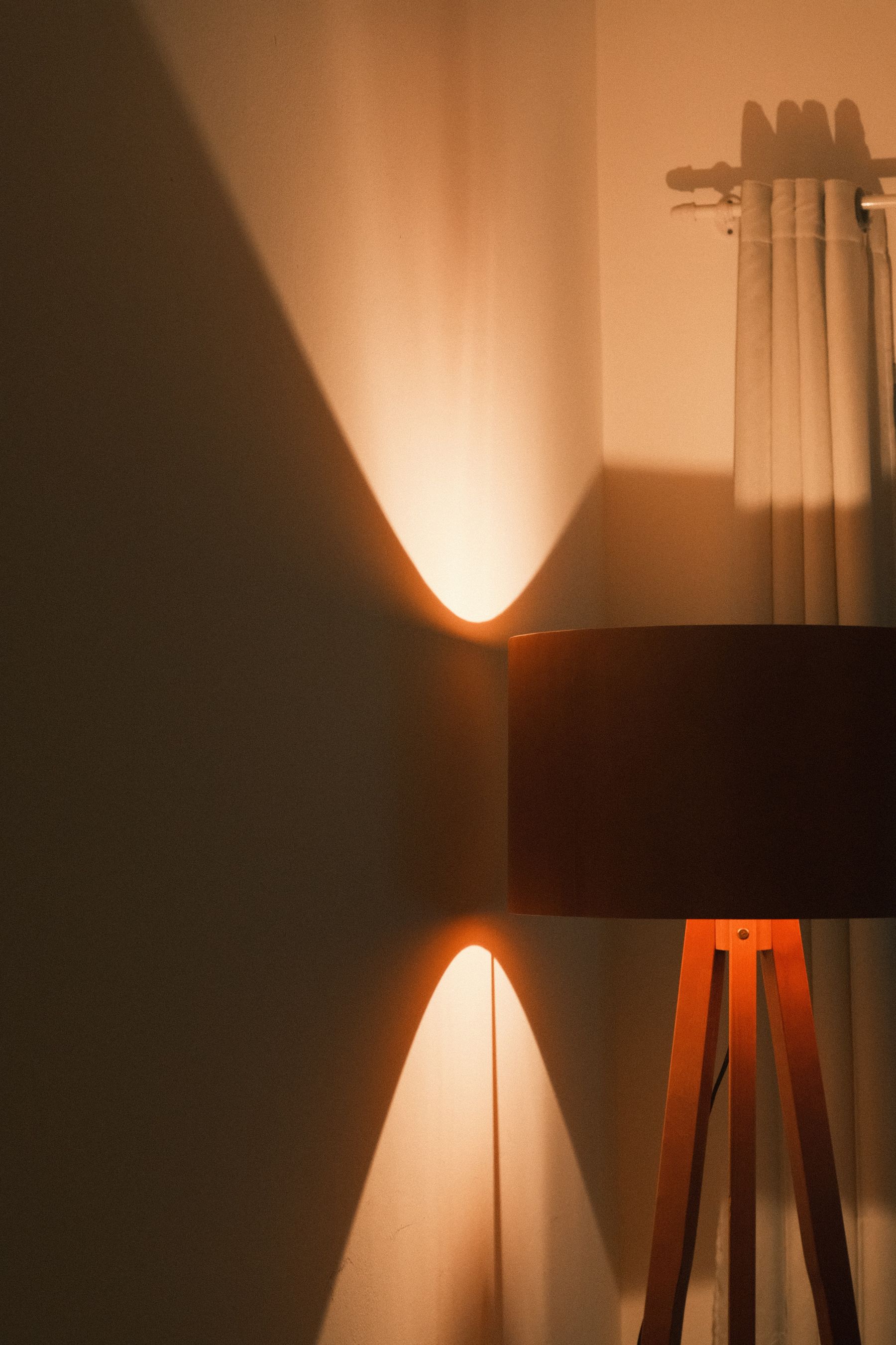 Warmly glowing freestanding tripod floor lamp in a dark interior