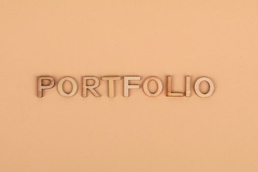 Close-up of wooden letters spelling 'PORTFOLIO' on a yellow background, offering creative copyspace.