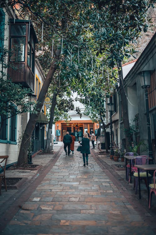 View of Pedestrians Walking in an Alley between Buildings in City 