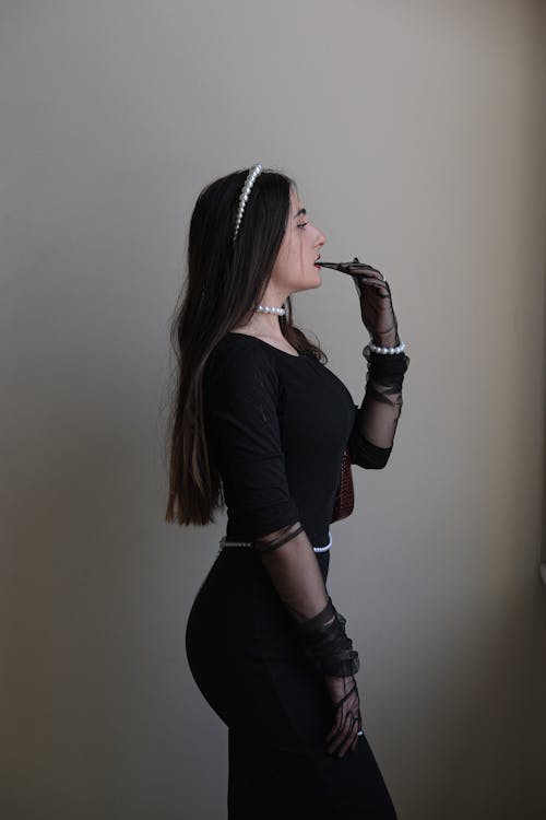 A Side View of a Woman in Black Dress with Her Hand on Her Mouth
