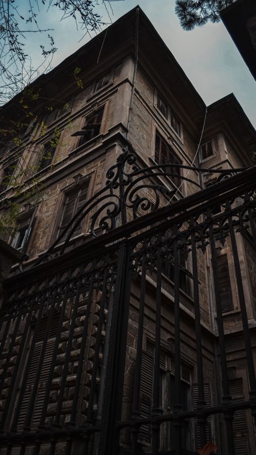 Free Dramatic view of an urban residential building and ornate iron gate at twilight, showcasing historic architecture. Stock Photo