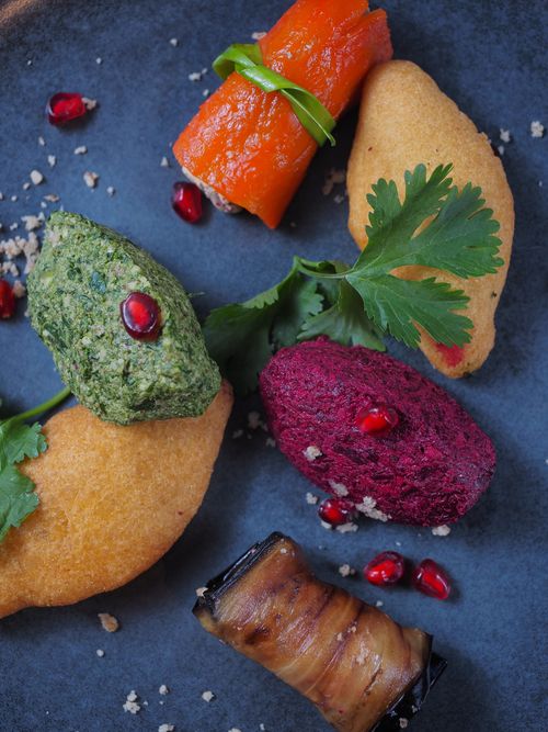 Free Colorful assortment of fresh appetizers on a blue plate, garnished with pomegranate seeds and herbs. Stock Photo
