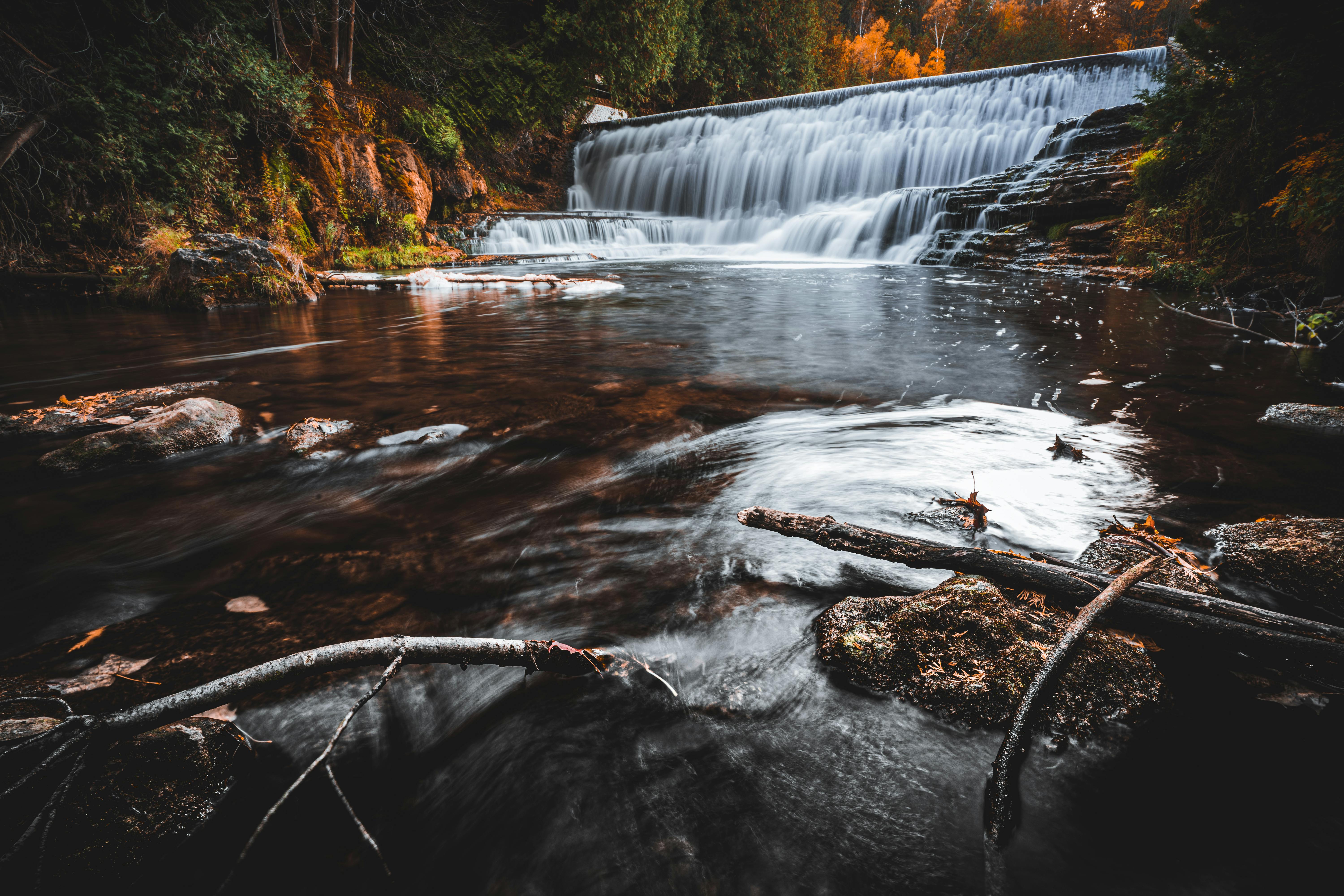 A tranquil waterfall surrounded by vibrant autumn foliage in Canada, showcasing nature's beauty.